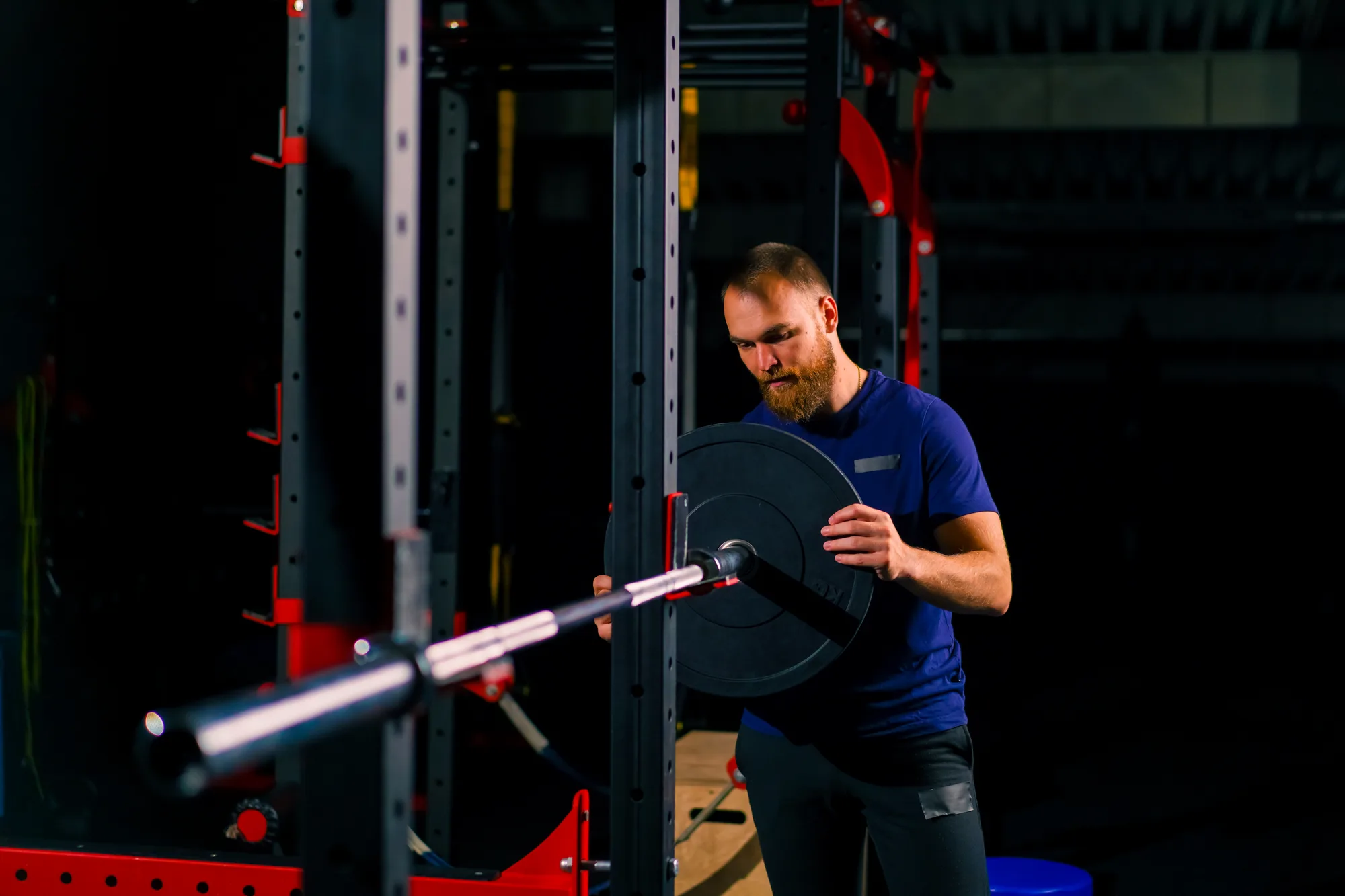 male athlete trainer adds weight to the barbell in the gym increases the load on the body