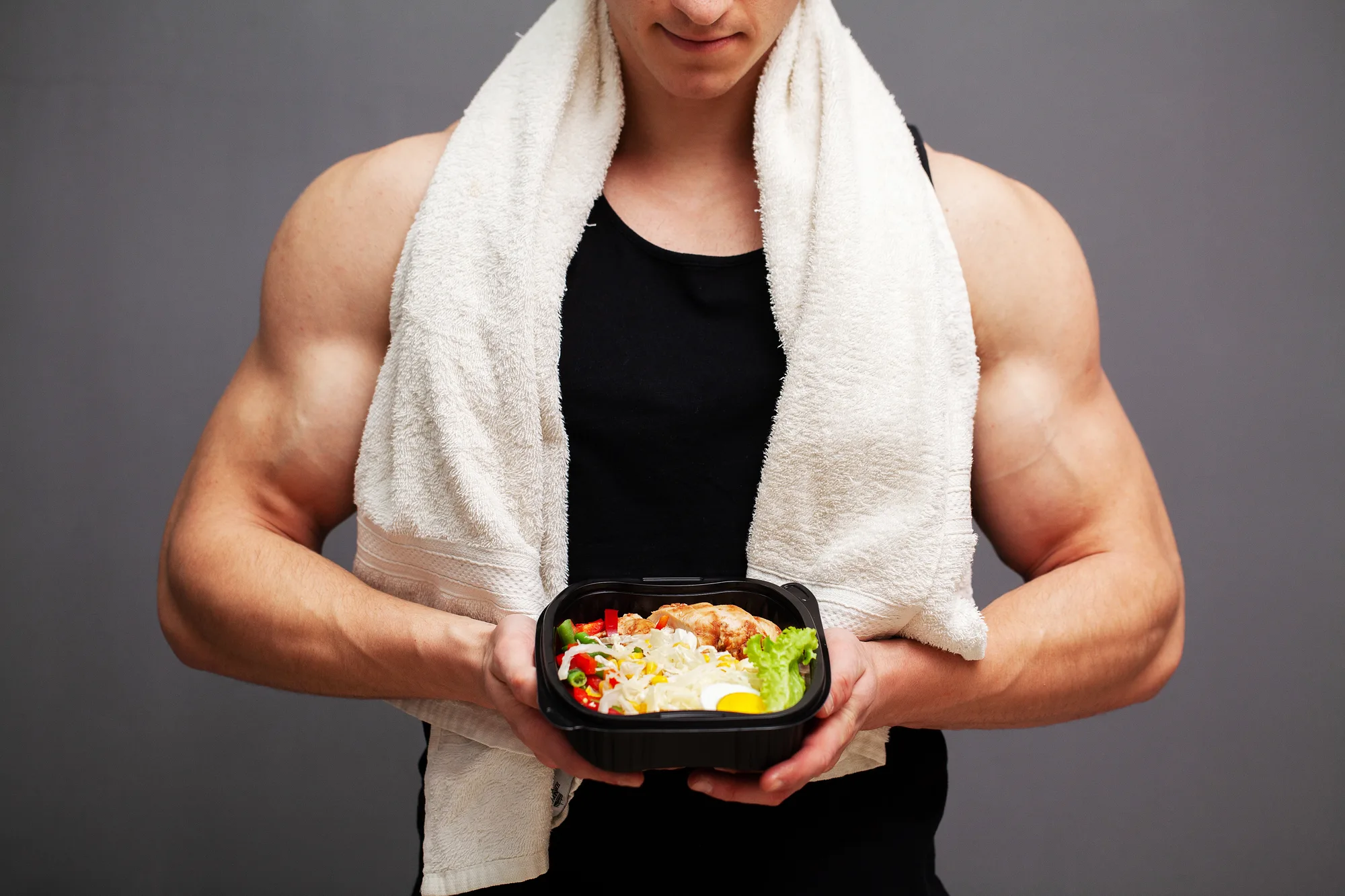 Nahaufnahme eines Mannes, der eine Box voller proteinreicher Lebensmittel für die Sporternährung hält.