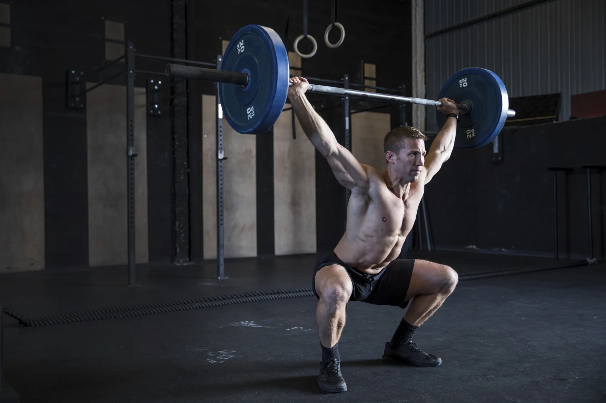 Man exercising in gym, using barbell, front squat position