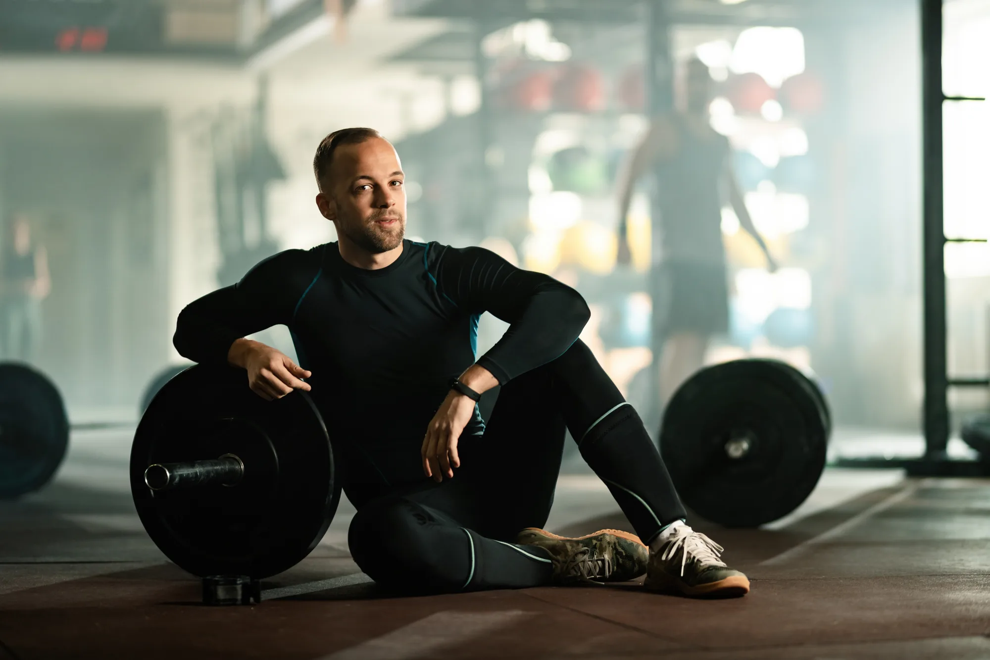 Young athletic man relaxing on the floor during weight training in a gym.