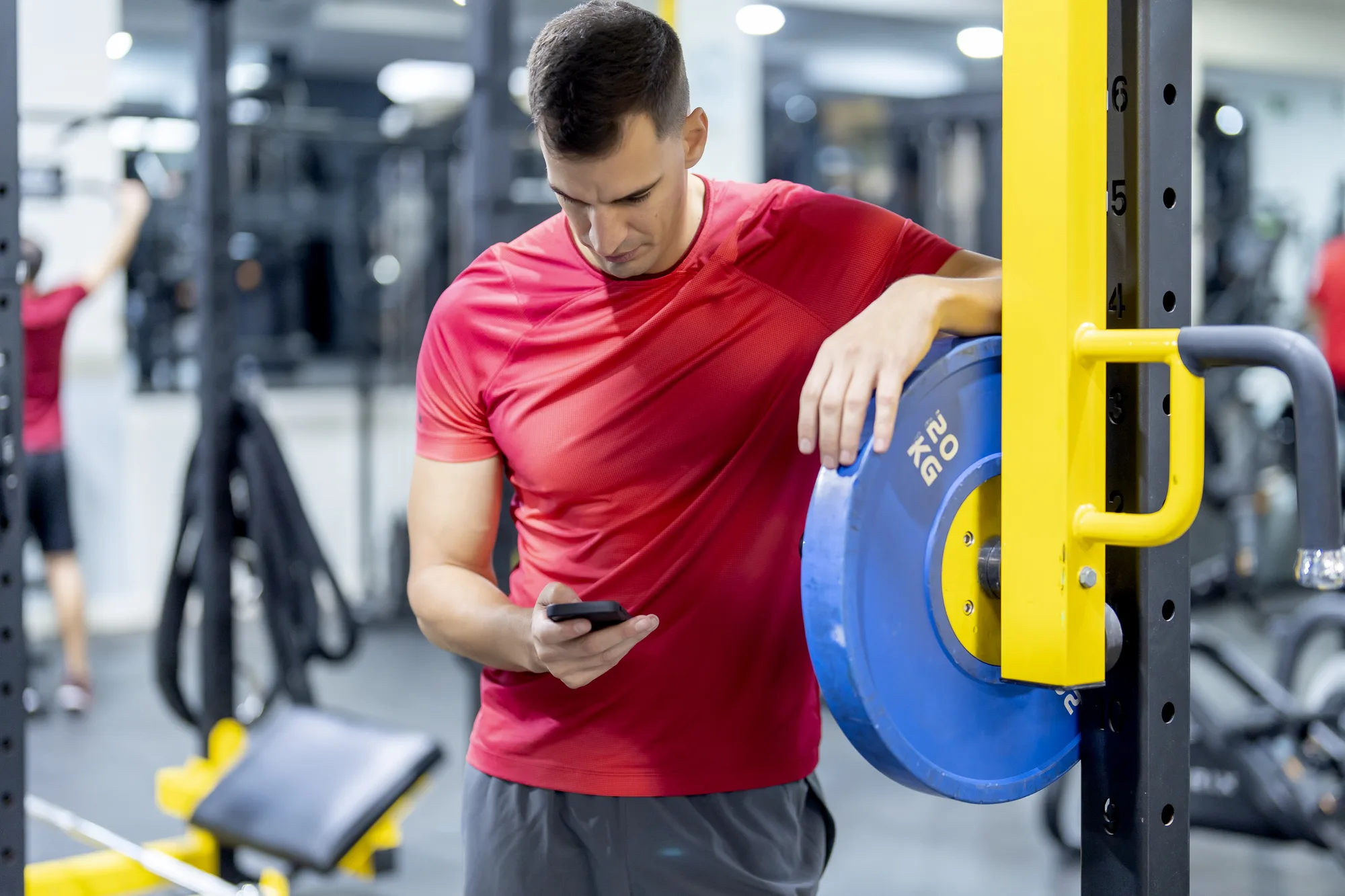 Strong athlete using cell phone in gym