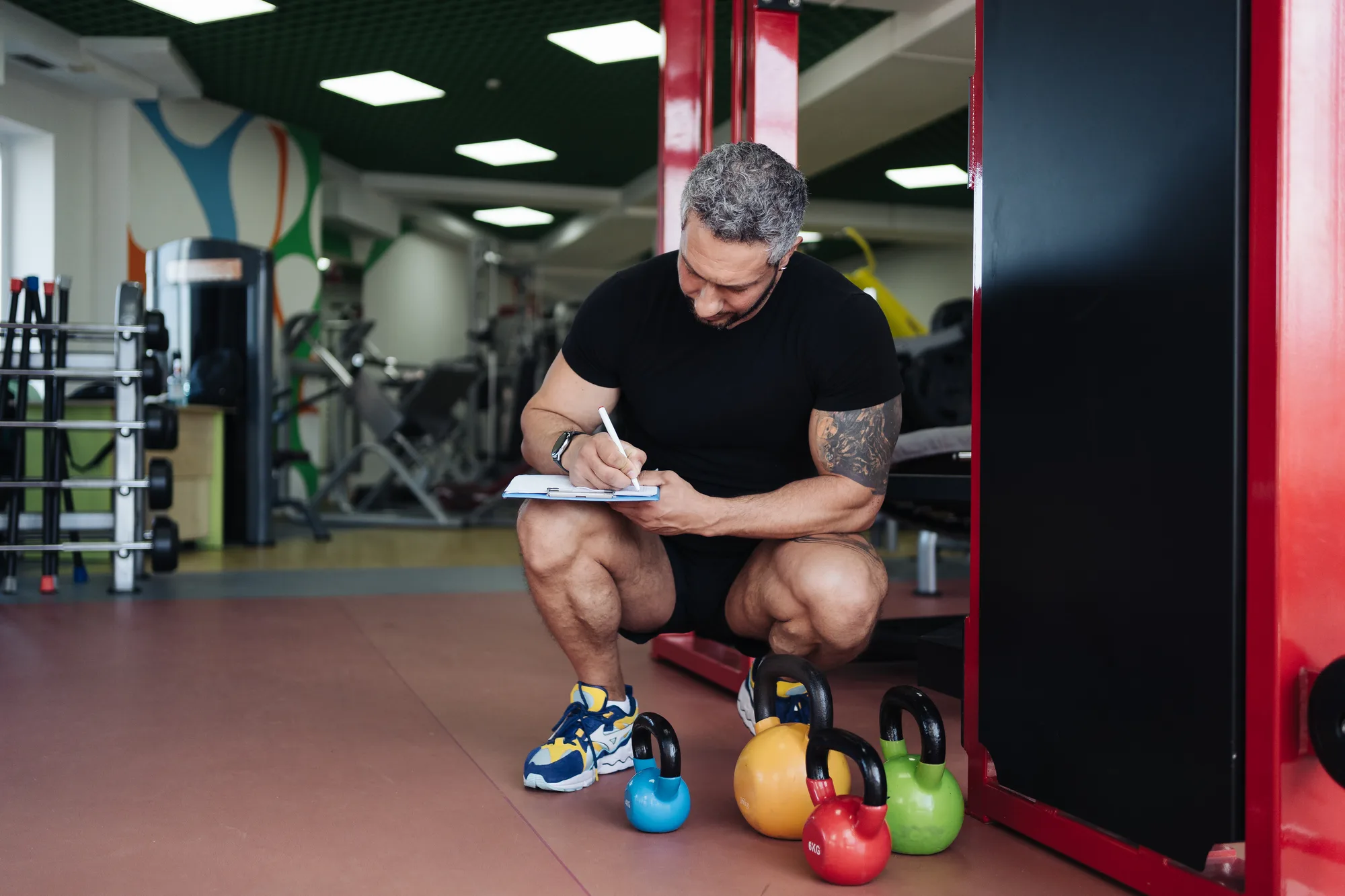 Personal fitness trainer writing a workout on gym background