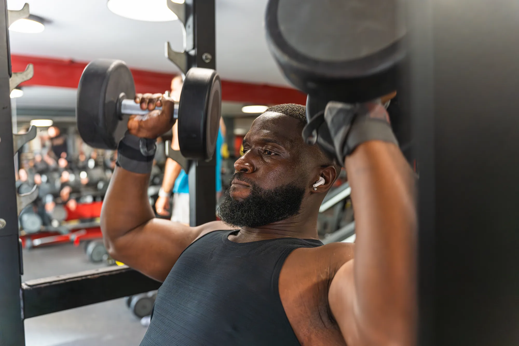 Black bodybuilder lifting dumbbells at neighborhood gym