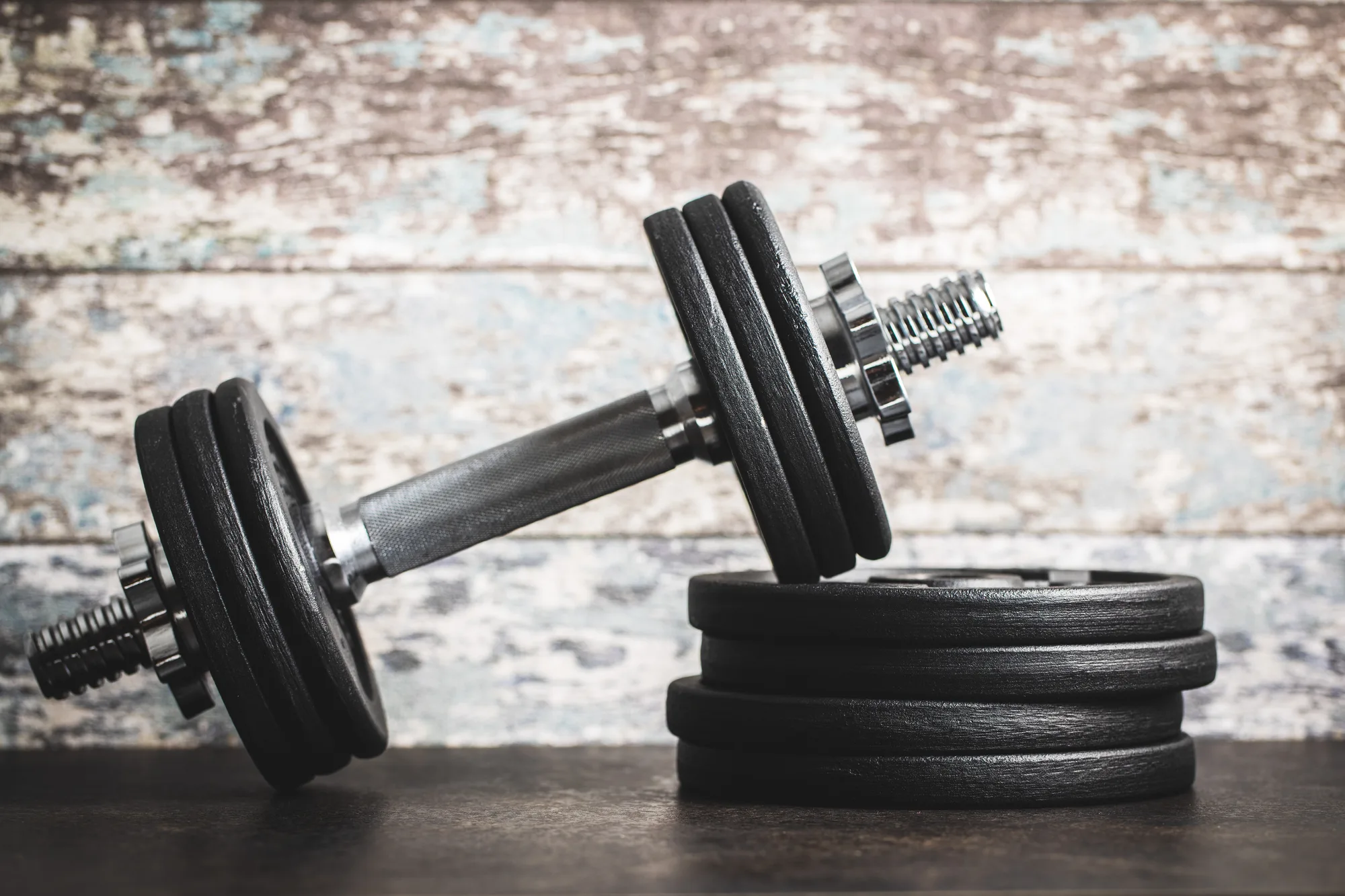 Iron dumbbells before old wooden wall.